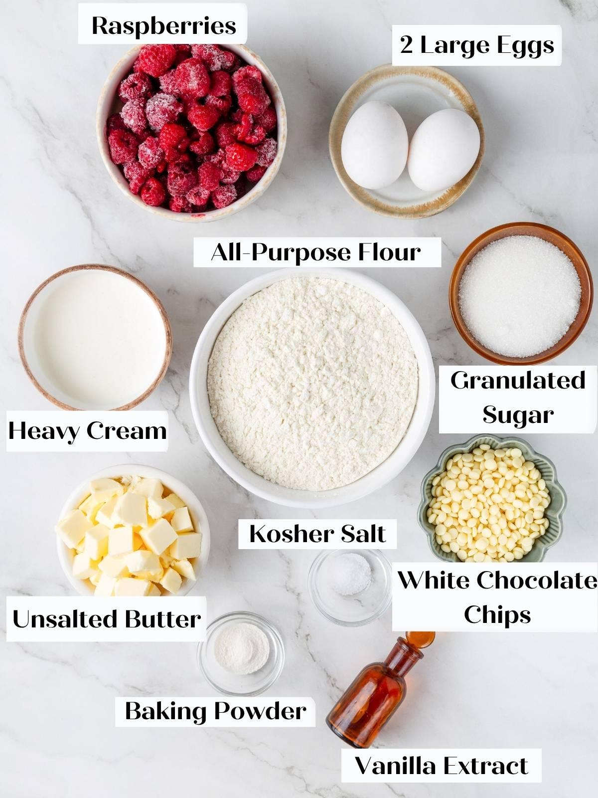 Labeled bowls of raspberries, eggs, flour, sugar, butter, cream, white chocolate chips, baking powder, salt, vanilla.