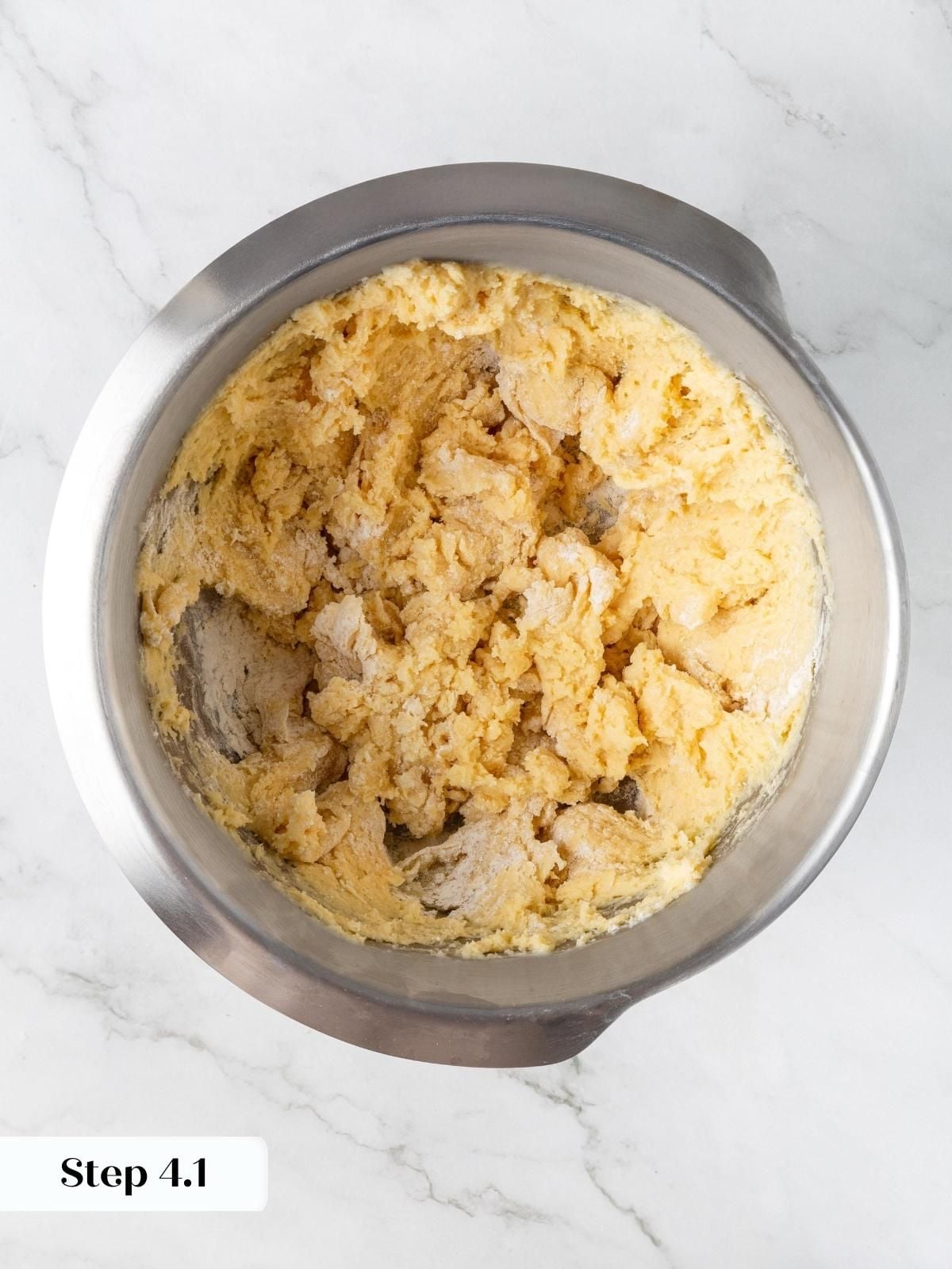 Shaggy scone dough just incorporated in a stainless steel stand mixer bowl after adding wet ingredients.