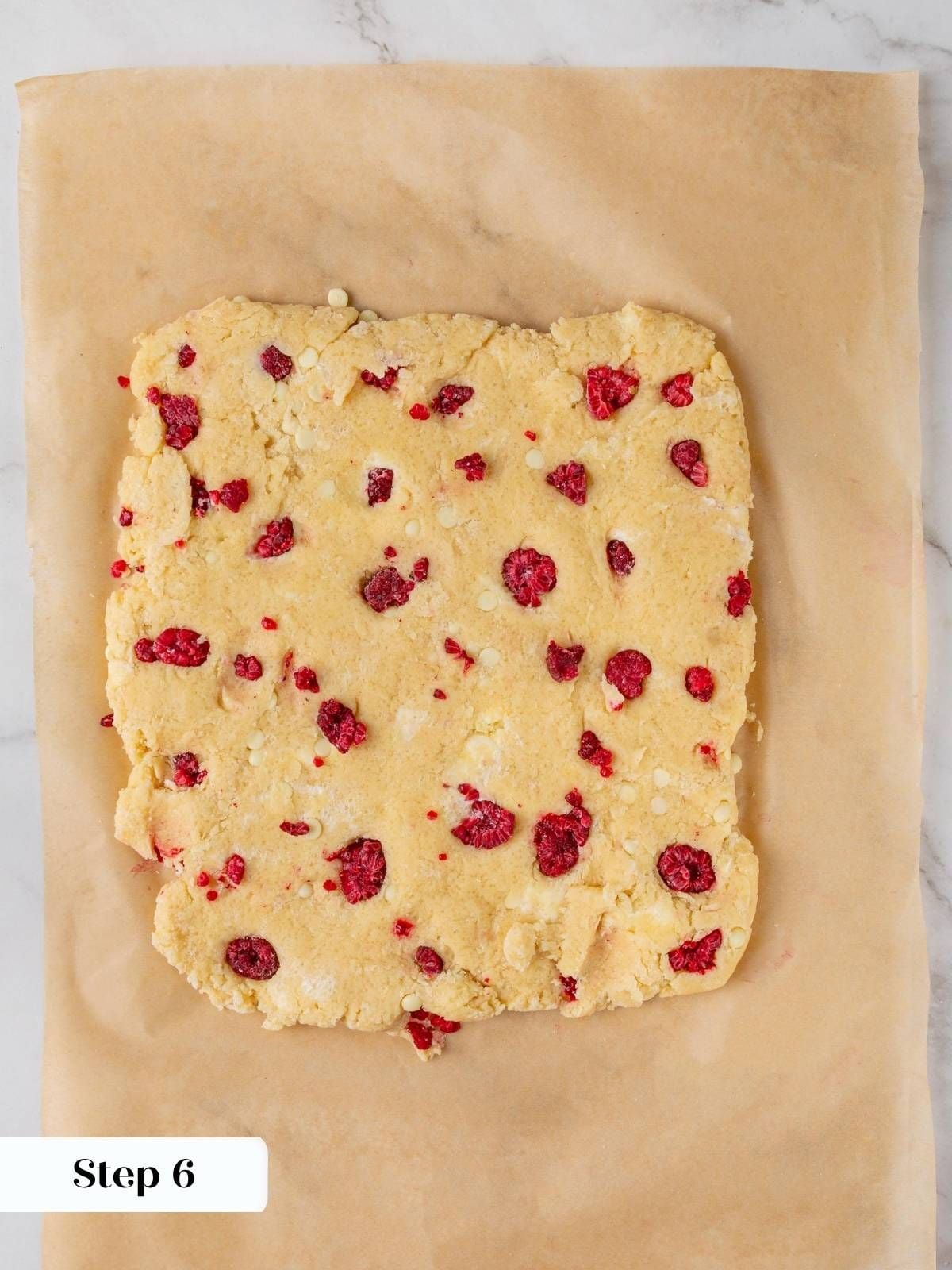 Scone dough pressed into a six-inch square half an inch thick on parchment paper before cutting.