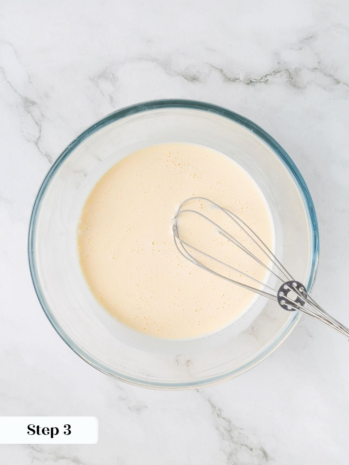 Eggs, heavy cream, and vanilla whisked together until smooth in a glass bowl with a whisk.