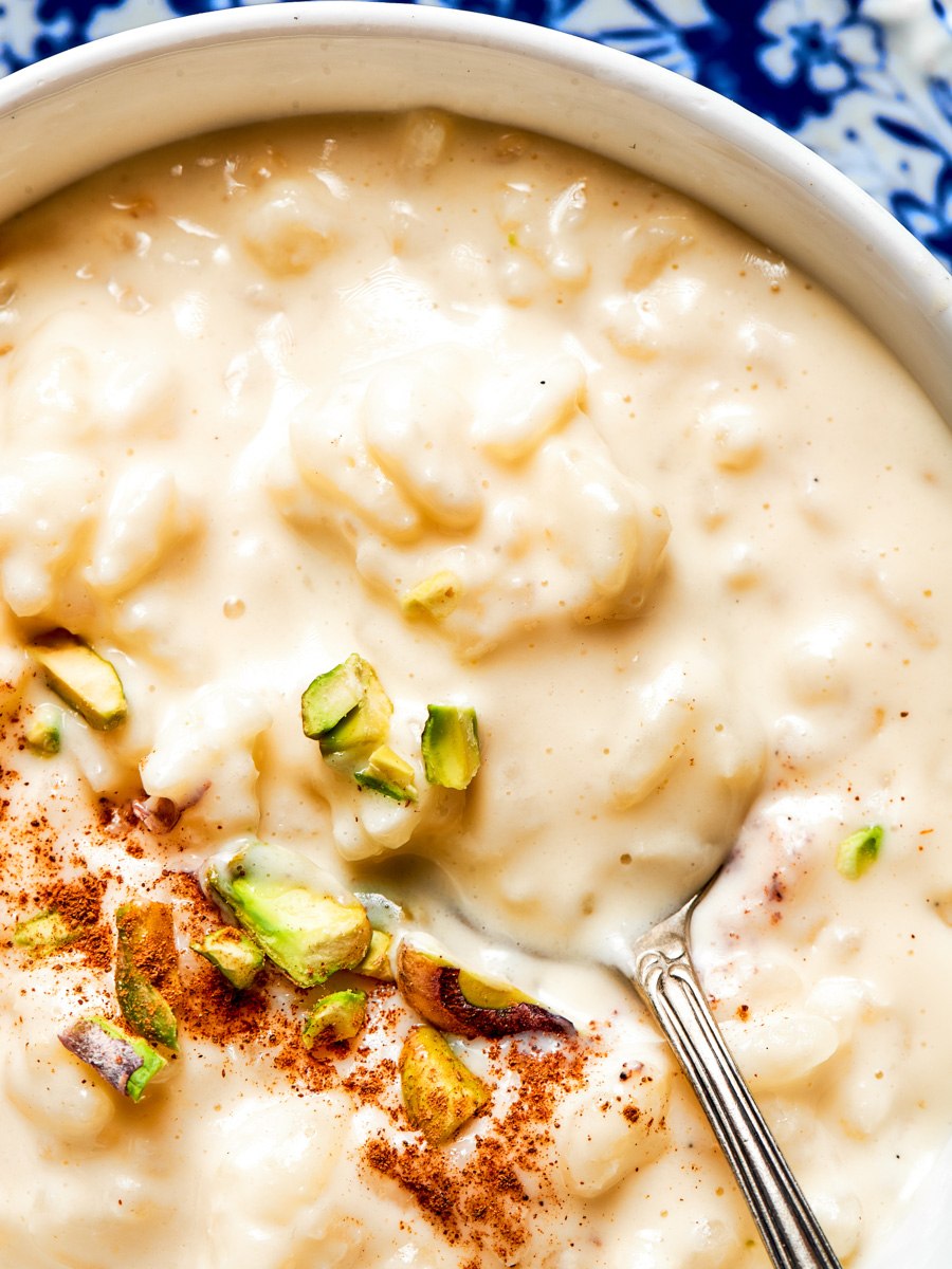Tight framing of rice pudding recipe at the rim of a vintage blue floral china bowl.