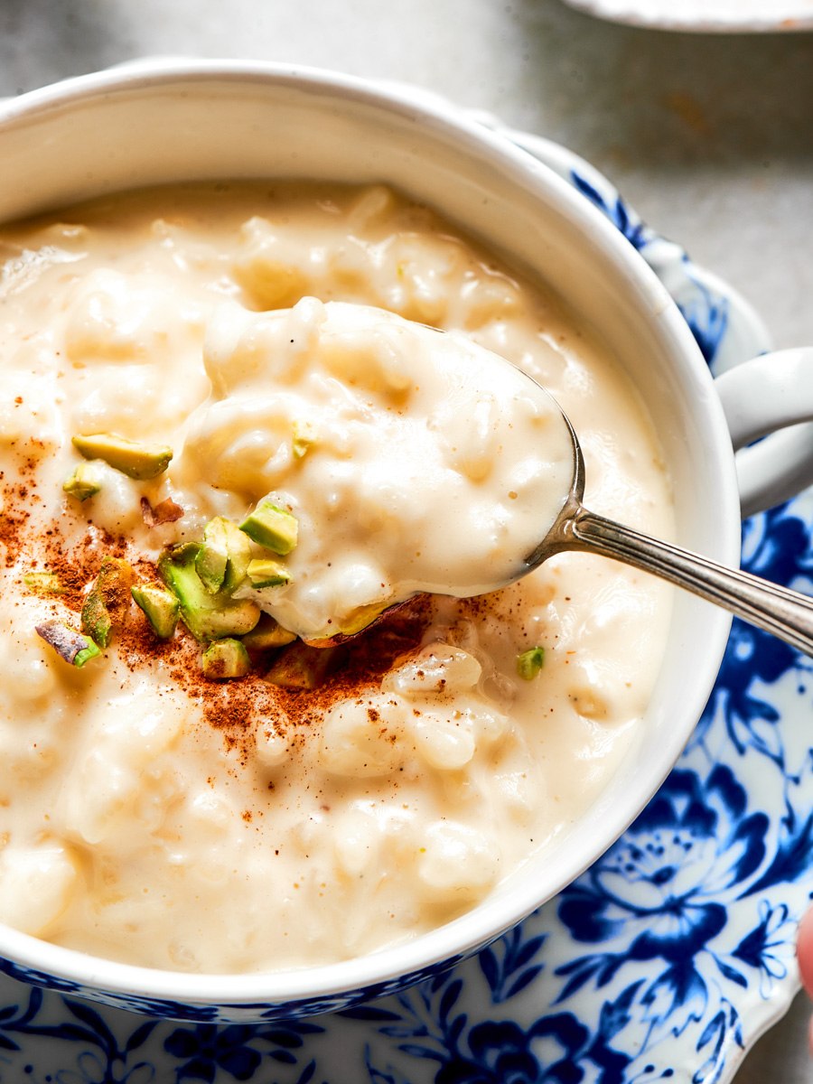 Detail of creamy rice pudding recipe being lifted on a vintage spoon over the bowl.