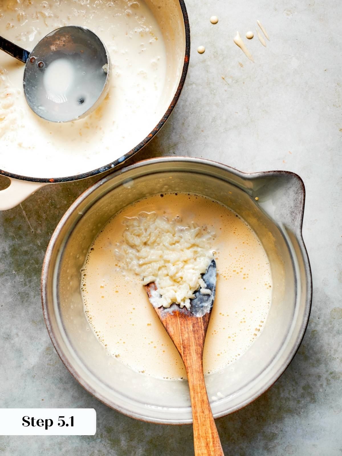Hot rice mixture being ladled slowly into whisked egg yolks to temper for rice pudding recipe.