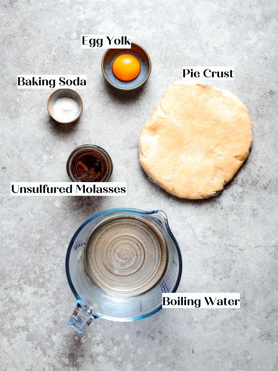 Egg yolk, molasses, baking soda, water, and pie dough gather for the shoofly pie filling.
