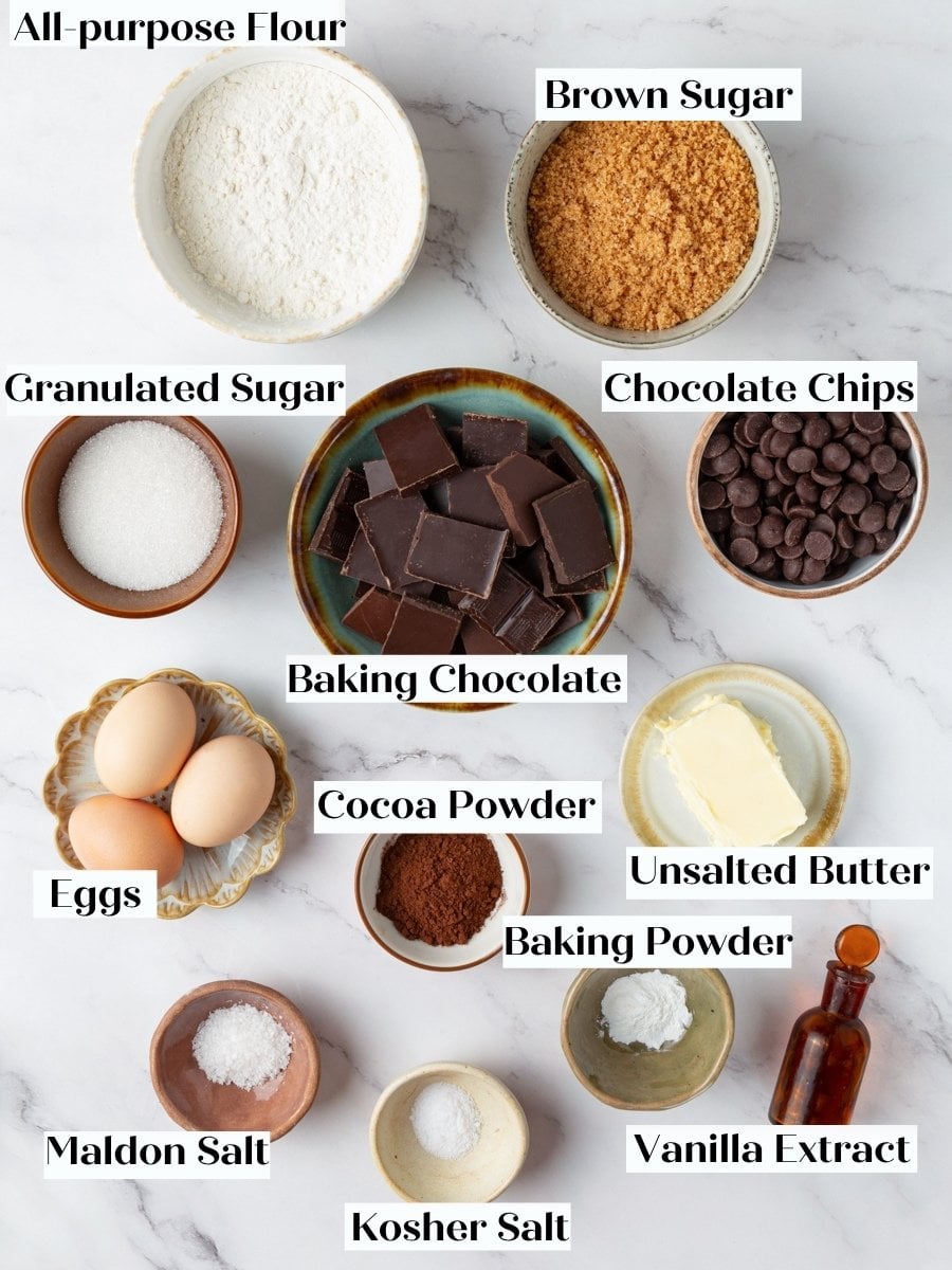 Bowls of flour, cocoa, chopped chocolate, eggs, butter, and sugars laid out for brownie cookies.