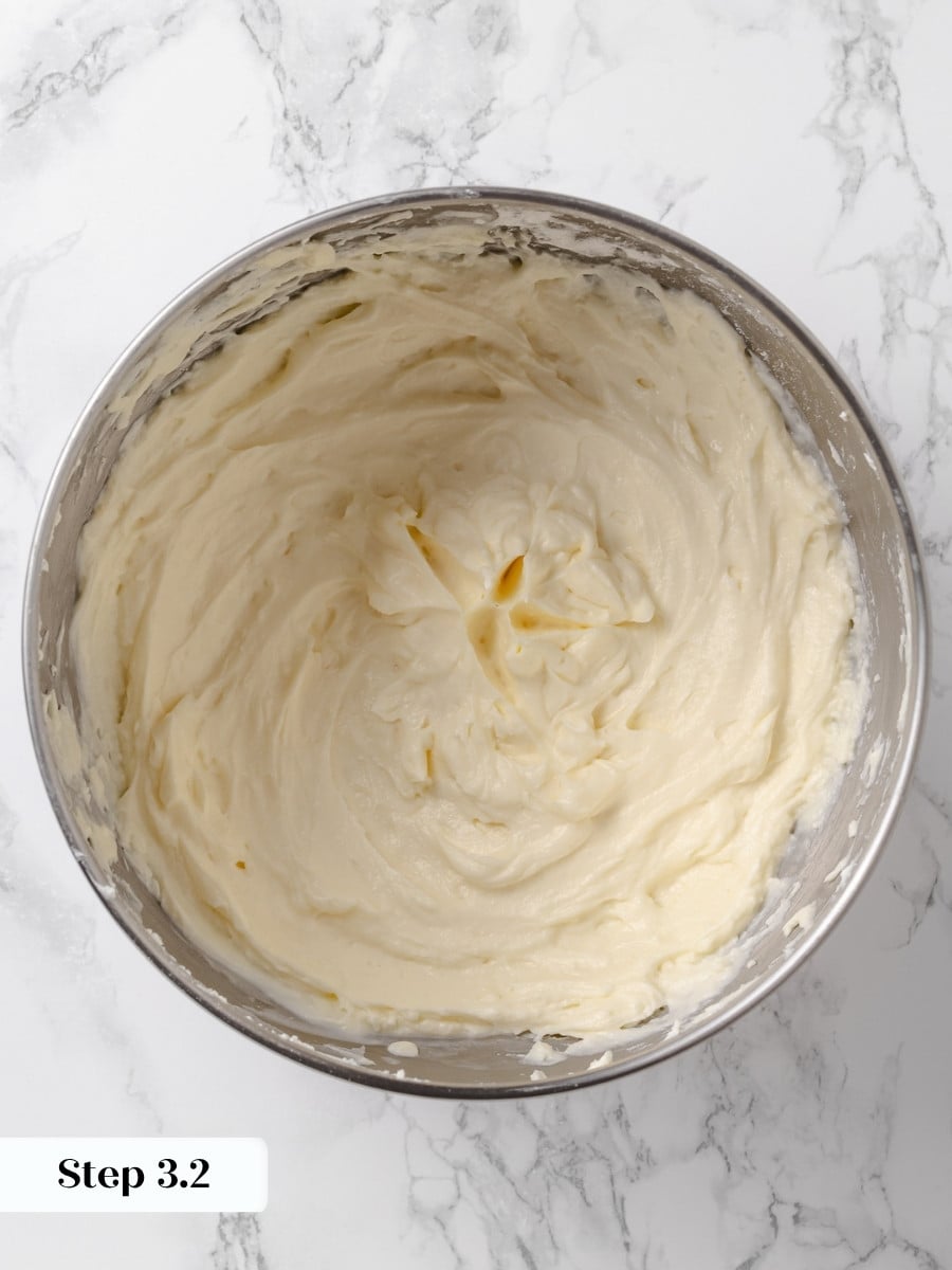 Finished cream cheese buttercream, smooth and glossy, in a stainless steel mixing bowl.