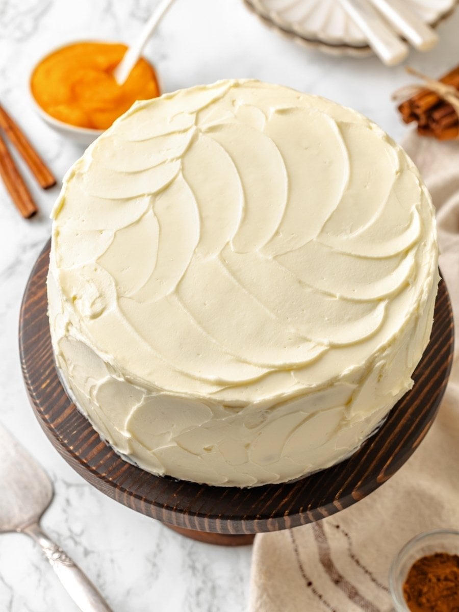 Warm styling with cinnamon and pumpkin puree frames the finished pumpkin cake as a fall centerpiece.