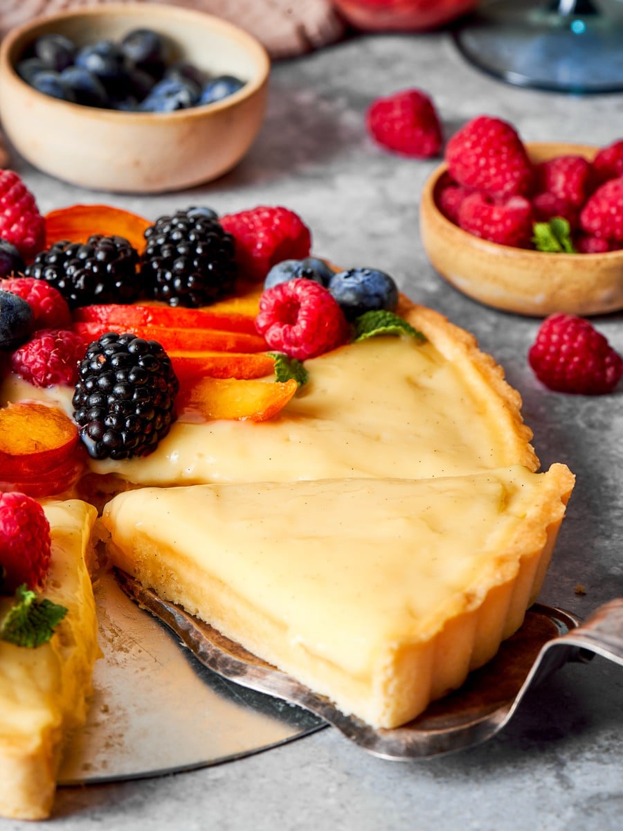 Lifting the first slice free shows how cleanly a chilled fruit tart cuts.