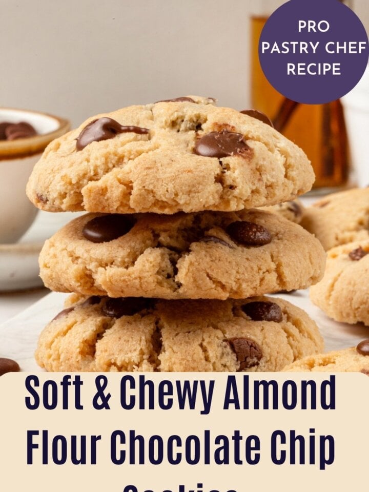 Stack of three thick almond flour chocolate chip cookies with melty chocolate on top and cinnamon sticks behind