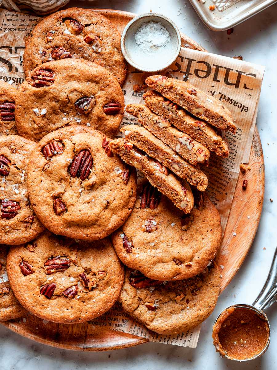 Halved butter pecan cookies reveal toasted pecan pieces inside thick, chewy centers with crisp golden edges.