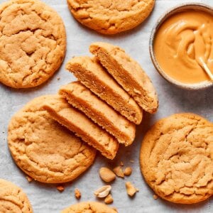 Cut and whole together show the crackled top and soft interior of chewy peanut butter cookies.