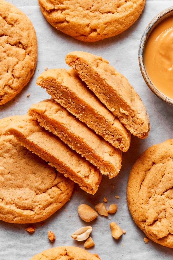 Cut and whole together show the crackled top and soft interior of chewy peanut butter cookies.