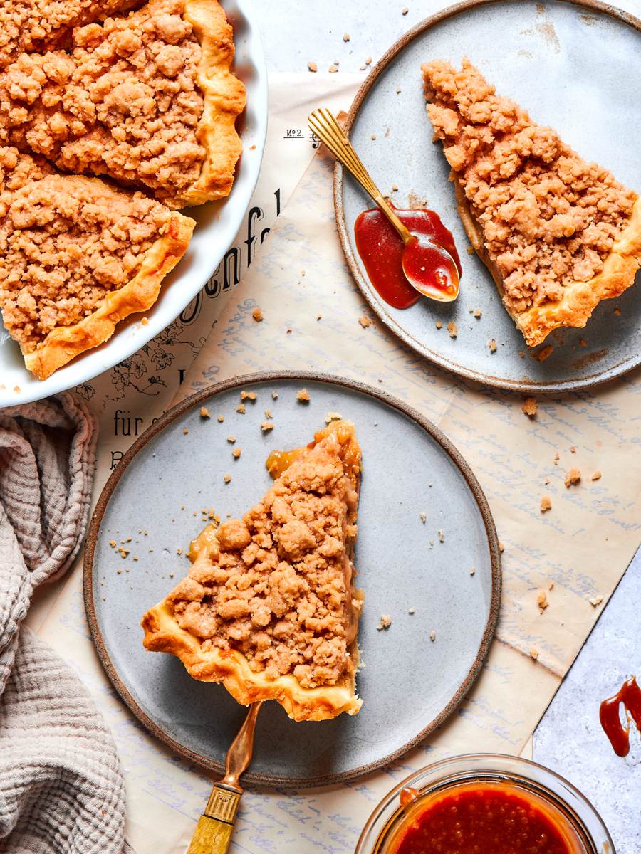 Slices of caramel apple tart are served with a spoonful of salted caramel alongside.